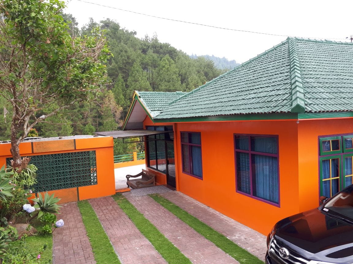 Tampak samping villa oranye beratap hijau