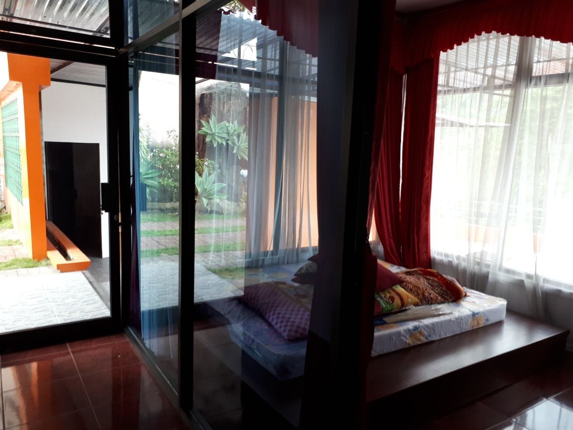 Kamar tidur dengan kelambu merah menghadap taman